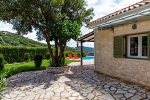 a tree in a stone walkway next to a house at Villa Melody Private Pool Villa with Mountain Views in Fternón +24 photos