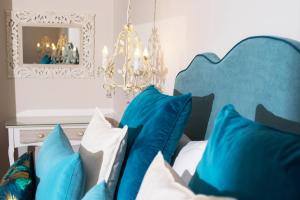 a bed with blue and white pillows and a chandelier at Ammos Boutique Apartments & Suites in Malia