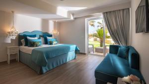 a bedroom with a blue bed and a chair at Ammos Boutique Apartments & Suites in Malia