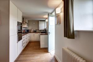 una pequeña cocina con armarios blancos y un pasillo en The Cottage Llyn Peninsula, en Nefyn