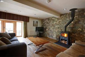 sala de estar con pared de piedra y chimenea en The Cottage Llyn Peninsula, en Nefyn
