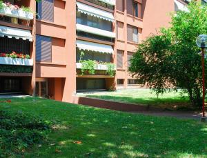 an apartment building with a green lawn in front of it at Home & Pet - Fiori in Basiglio