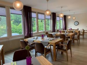 un comedor con mesas, sillas y ventanas en Hotel am Siebenpfennigsknapp, en Lünen