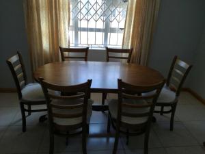 a dining room table with chairs and a window at The Crescent Guesthouse on Waterfall in Durban