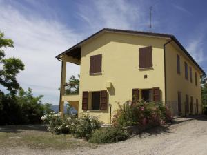 a yellow house with brown shuttered windows at Belvilla by OYO Gesso Piccolo in Sassoleone
