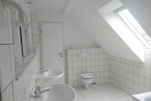 a white bathroom with a toilet and a sink at Sonniges Häuschen mit Garten in Braunschweig