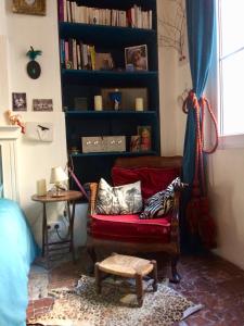 a living room with a red couch and a book shelf at Le Boudoir d'artiste in Semur-en-Auxois