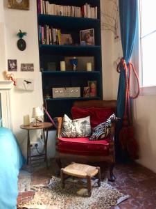 ein Wohnzimmer mit einer roten Couch und einem Bücherregal in der Unterkunft Le Boudoir d'artiste in Semur-en-Auxois