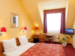 Pokój hotelowy z łóżkiem, biurkiem i oknem w obiekcie Cloister Inn Hotel w Pradze