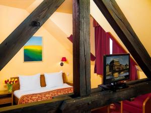 um quarto com uma cama e uma televisão num quarto em Cloister Inn Hotel em Praga