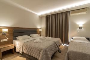 um quarto de hotel com duas camas e uma janela em Sintrivanis Resort Beach em Paralia Skotinas
