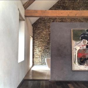 a room with a brick wall and a painting of a motorcycle at Les Rochers in Cerisy-la-Forêt