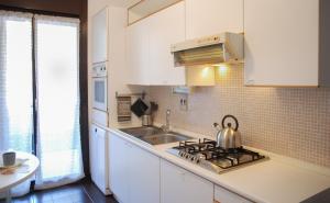 a kitchen with white cabinets and a tea kettle on the stove at Home & Pet - Fiori in Basiglio
