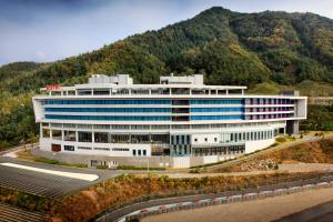 an office building with a mountain in the background at Take Hotel & Resort Inje Speedium in Inje