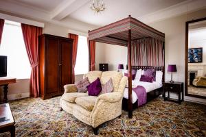a bedroom with a canopy bed and a chair at Mangreen Country House in Norwich