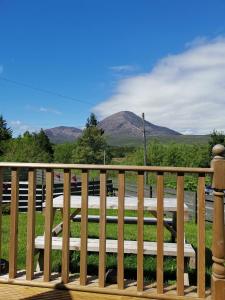 a wooden bench on a deck with mountains in the background at Tigh Beag na h'aibhne in Broadford