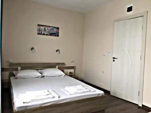 a bedroom with a bed with white sheets and a door at "Бербатови 1" in Ravda