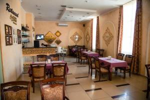 una sala da pranzo con tavoli, sedie e camino di Silk Way Hotel ad Aqtau