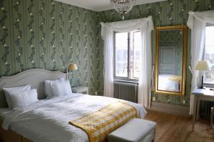 a bedroom with a bed with green wallpaper and a mirror at Thottska Villan in Strömsholm