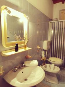 een badkamer met een wastafel, een toilet en een spiegel bij Casa Vacanza Mariaoliva in Menfi