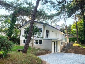a white house with a tree in front of it at Villa Greif Pineta in Lignano Sabbiadoro
