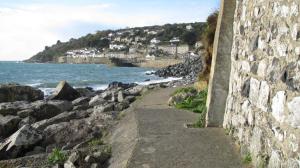 a stone wall next to a beach with the ocean at Penzer Cottage in Penzance