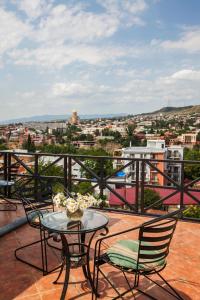 eine Terrasse mit einem Tisch und Stühlen auf dem Balkon in der Unterkunft Caravan Villa in Tbilisi City