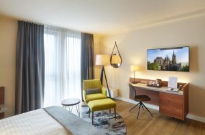a hotel room with a bed and a desk and a chair at Aquis Grana City Hotel in Aachen