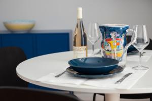 Laurus apartments في تراباني: طاولة بيضاء مع وعاء أزرق وكؤوس للنبيذ