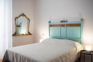 um quarto com uma cama com uma cabeceira azul e um espelho em Laurus apartments em Trapani