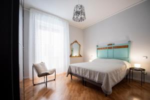 um quarto com uma cama, uma cadeira e uma janela em Laurus apartments em Trapani