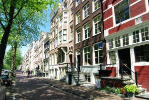 a city street with tall buildings on a sunny day at 1637: Historic Canal View Suites in Amsterdam