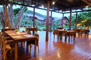 ein Restaurant mit Holztischen und -stühlen auf einem Holzboden in der Unterkunft Koh Ma Beach Resort - SHA Extra Plus in Mae Haad
