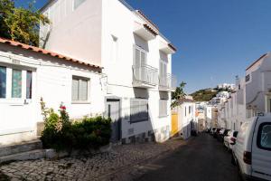 una calle estrecha con edificios blancos y coches aparcados en De Hofnar Apartments Albufeira en Albufeira