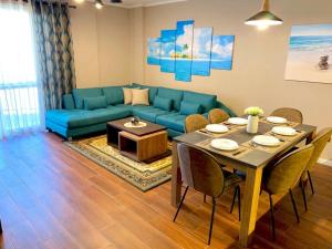 a living room with a blue couch and a table and chairs at EKA Luxury Two-Bedroom Premium Apartment 2 in Durrës