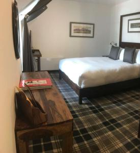 a hotel room with a bed and a wooden table at Edinbane Lodge in Edinbain