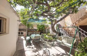 a patio with a table and chairs under a tree at Apartmani Marko in Makarska