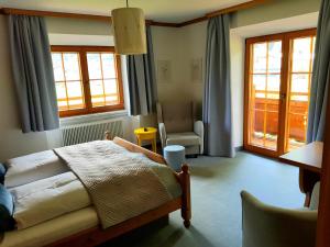 a bedroom with a bed and a chair and windows at Pension Rangger in Radfeld