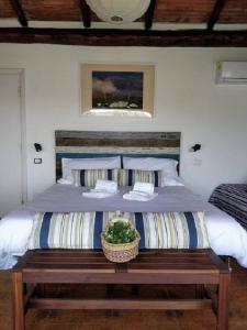 a bedroom with a large bed with a wooden bench at Casa di Ester - villino con vista panoramica e giardino privato sulla collina di Porto Stefano - Monte Argentario - Vikey in Porto Santo Stefano
