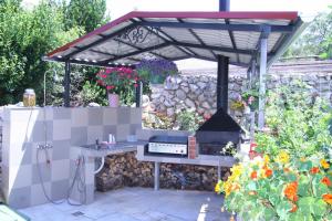 a barbecue grill in a garden with a stone wall at Villa Roze in Čižići