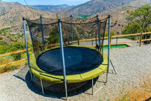 a yellow trampoline with a net on a hill at Complejo Rural El Mirador in Málaga