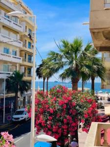 a street with flowers and palm trees and a building at Amiral Courbet Apartment in Juan-les-Pins