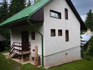 uma pequena casa branca com um telhado verde e um banco em Chata Renďo em Kokava nad Rimavicou