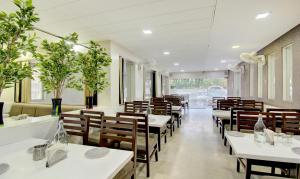 ein Restaurant mit weißen Tischen und Holzstühlen in der Unterkunft Treebo Trend Lalaji's Executive in Aurangabad