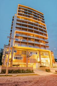 wysoki żółty apartamentowiec o zachodzie słońca w obiekcie Candeias Guarujá w mieście Guarujá
