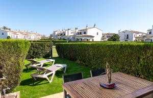 a garden with a wooden table and chairs and bushes at LA PLATERA " Seaview " in L'Estartit