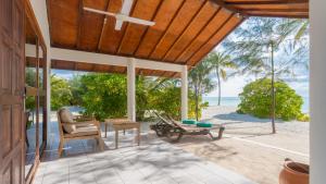 an outdoor patio with a table and chairs and the beach at Innahura Maldives Resort in Lhaviyani Atoll