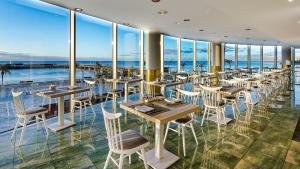 a restaurant with tables and chairs and large windows at Arrecife Gran Hotel & Spa in Arrecife
