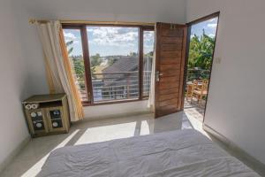 a bedroom with a bed and a large window at Pluto House in Canggu