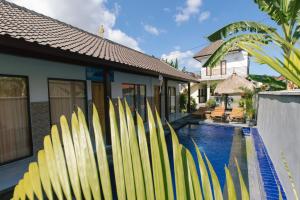 a row of surfboards leaning against a wall next to a swimming pool at Pluto House in Canggu